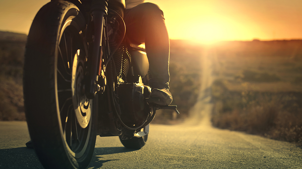 PERSON ON A MOTORCYCLE ON A ROAD AT SUNSET
