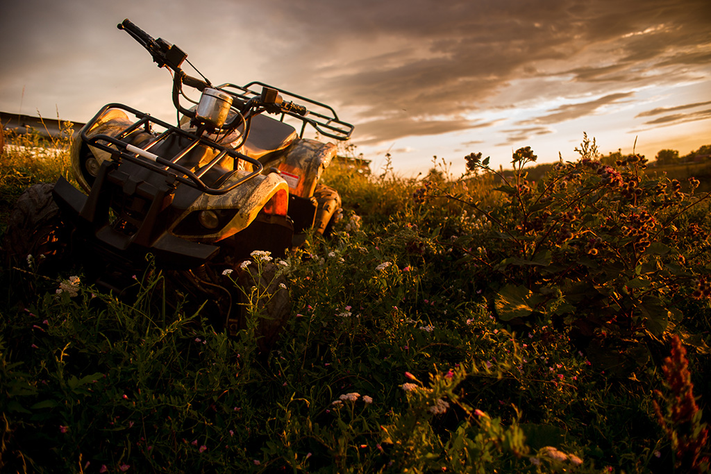ATV PARKED IN WILD BRUSH WITH A SUNSET