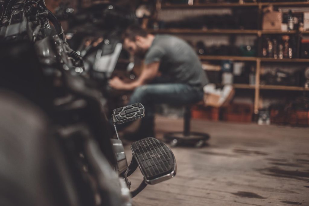 A MAN IN A GARAGE WORKING ON A MOTORCYCLE